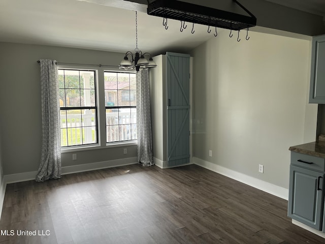 unfurnished dining area with a chandelier, dark wood-style flooring, baseboards, and a barn door