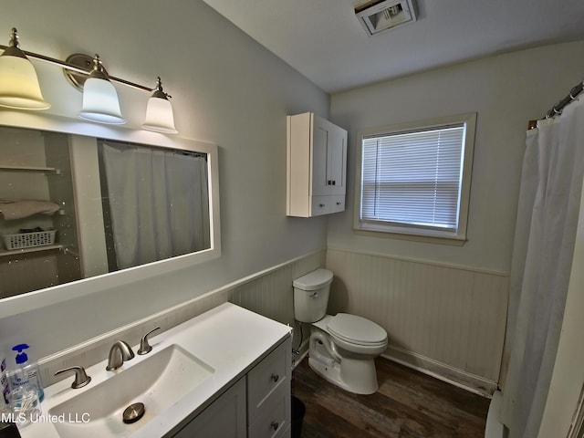 full bath featuring vanity, wainscoting, toilet, visible vents, and wood finished floors