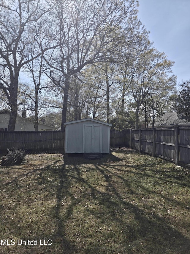 view of yard featuring an outdoor structure, a fenced backyard, and a storage unit