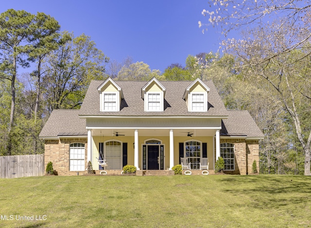 new england style home featuring a front yard, covered porch, and ceiling fan