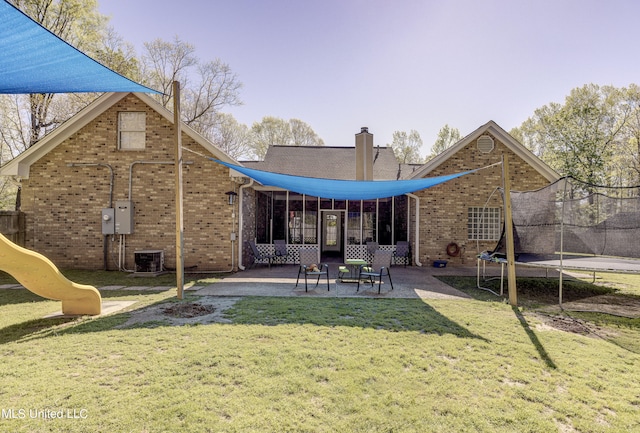 rear view of property featuring a yard, a patio, central AC unit, a trampoline, and a playground