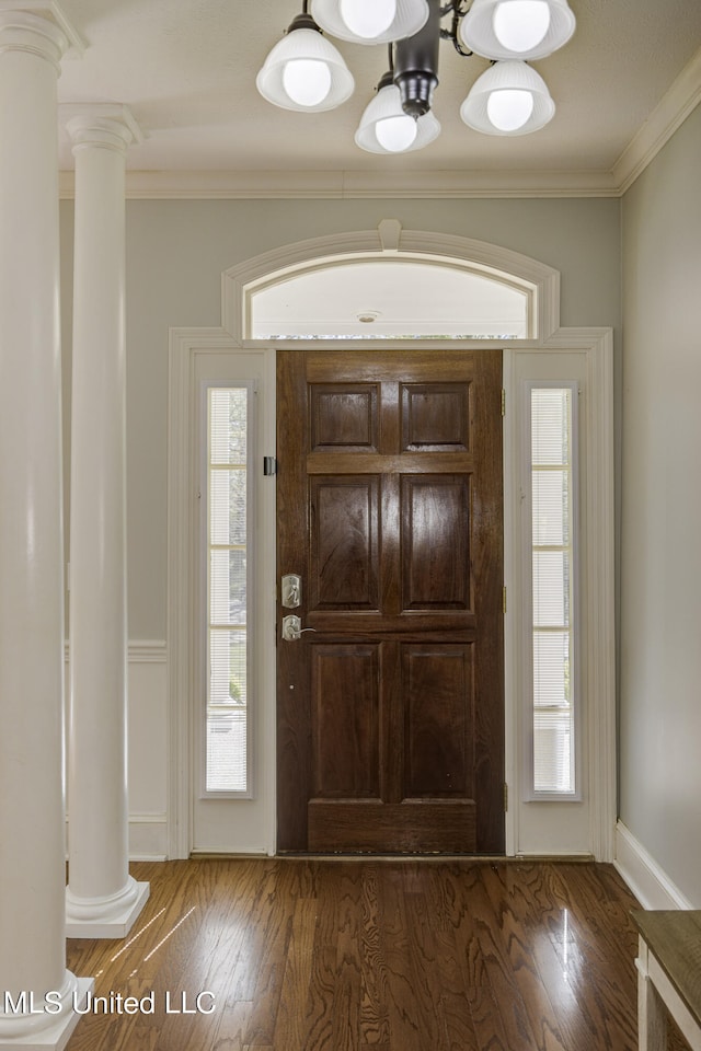 foyer featuring crown molding, dark hardwood / wood-style floors, and ornate columns