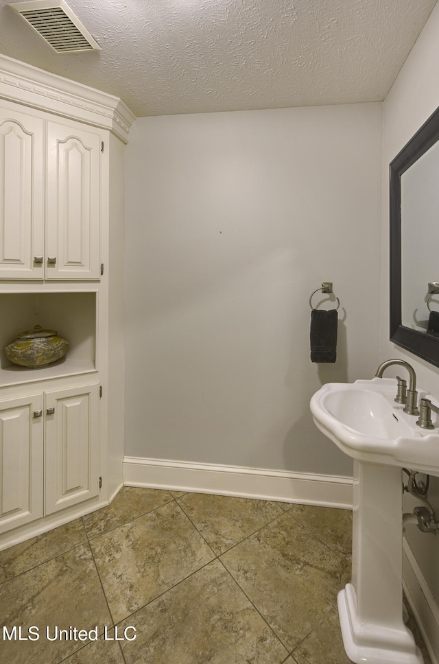 bathroom featuring a textured ceiling and tile patterned floors