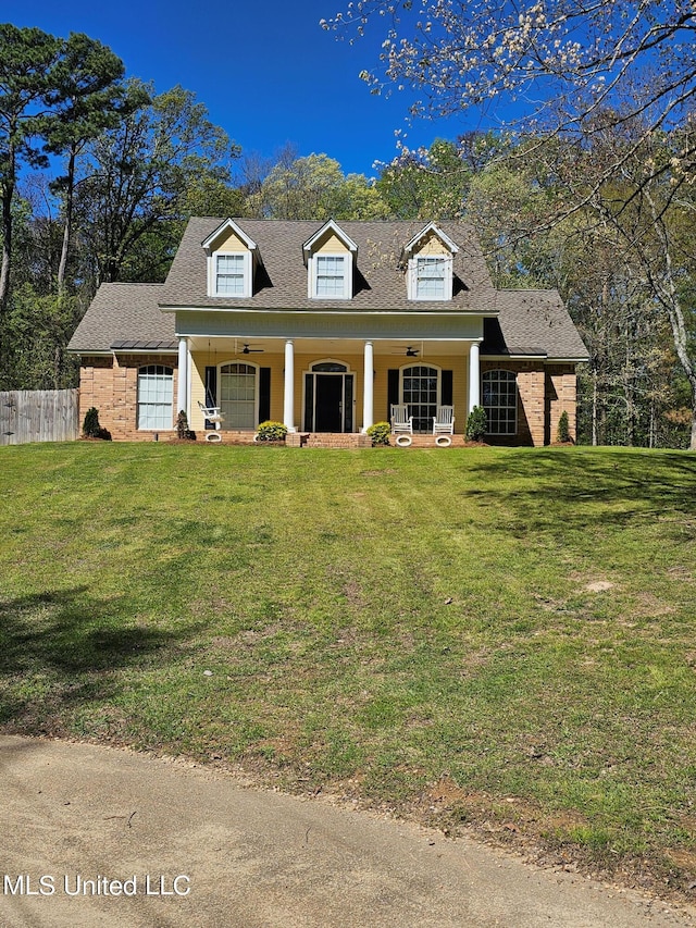 new england style home featuring covered porch and a front lawn