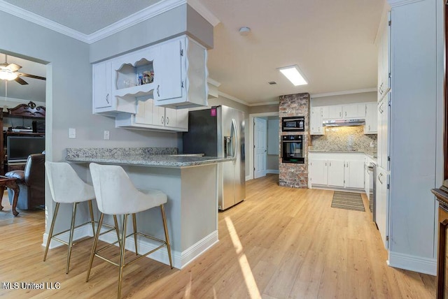 kitchen featuring a peninsula, black oven, built in microwave, stainless steel fridge, and under cabinet range hood