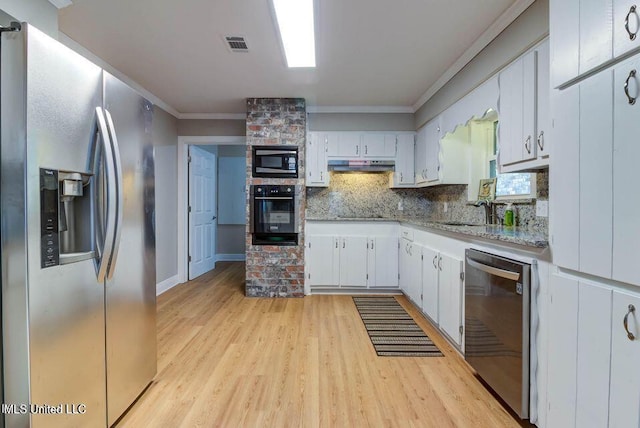 kitchen featuring under cabinet range hood, stainless steel appliances, light wood finished floors, tasteful backsplash, and crown molding