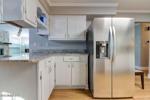 kitchen with light wood-type flooring, stainless steel fridge, and white cabinets