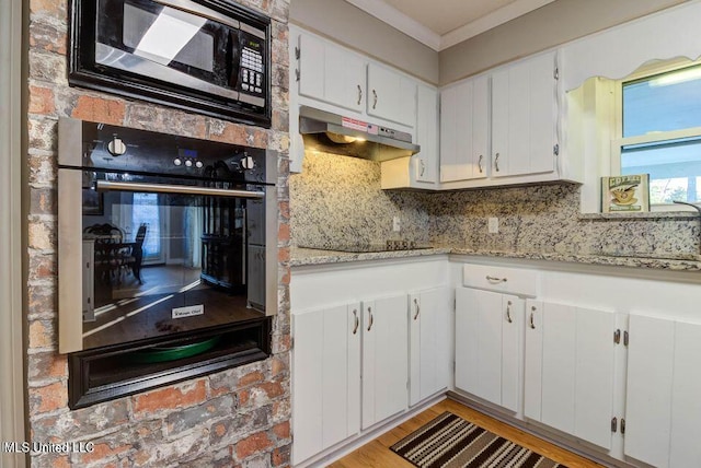 kitchen featuring a warming drawer, decorative backsplash, a sink, under cabinet range hood, and black appliances