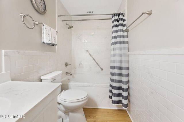 bathroom featuring toilet, visible vents, tile walls, and shower / tub combo with curtain