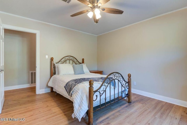 bedroom featuring baseboards, crown molding, visible vents, and wood finished floors