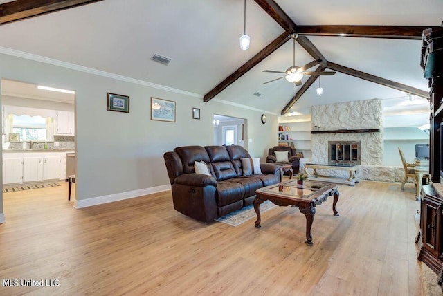 living room featuring lofted ceiling with beams, a fireplace, visible vents, and light wood-style floors