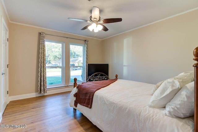 bedroom featuring a ceiling fan, baseboards, ornamental molding, and wood finished floors