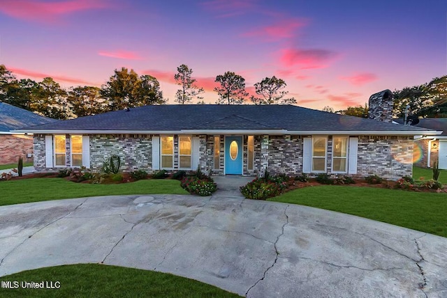 single story home with a chimney, a front lawn, and brick siding