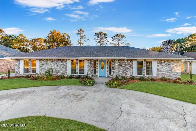 single story home with brick siding, a chimney, and a front lawn