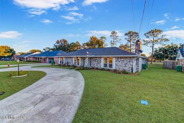 ranch-style house featuring a front yard, brick siding, driveway, and roof with shingles