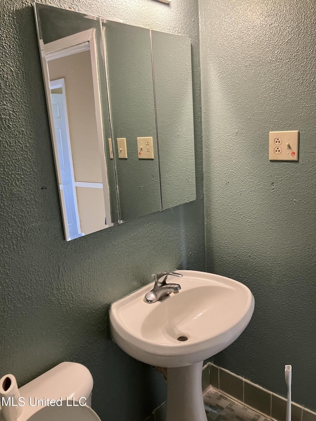 bathroom with toilet and a textured wall