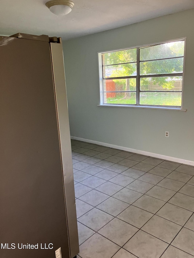 spare room with healthy amount of natural light, light tile patterned floors, and baseboards
