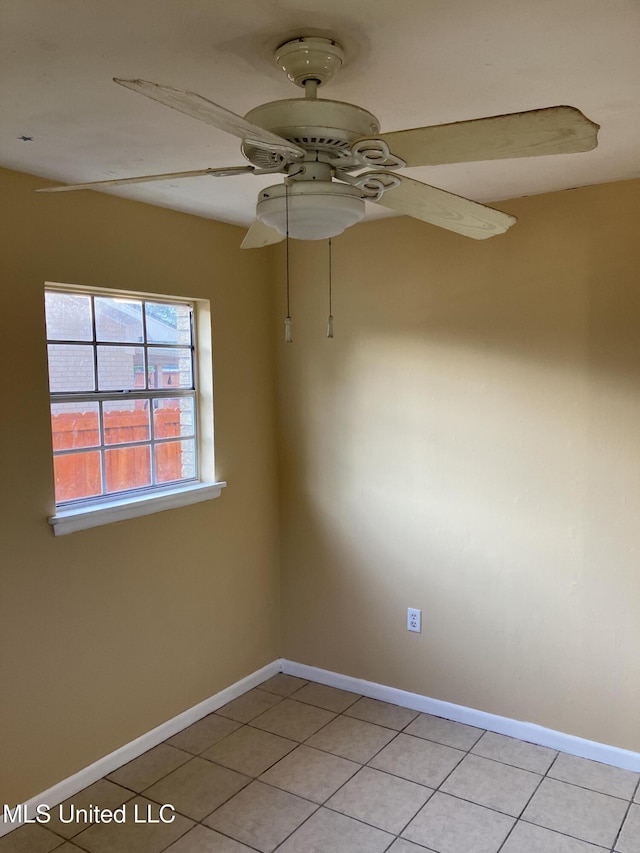 empty room featuring baseboards, light tile patterned floors, and a ceiling fan