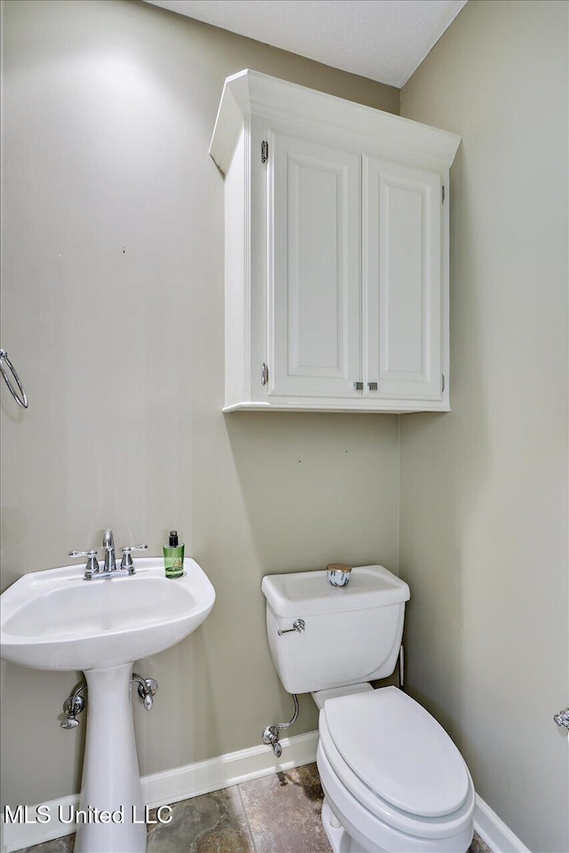 half bathroom featuring baseboards and toilet