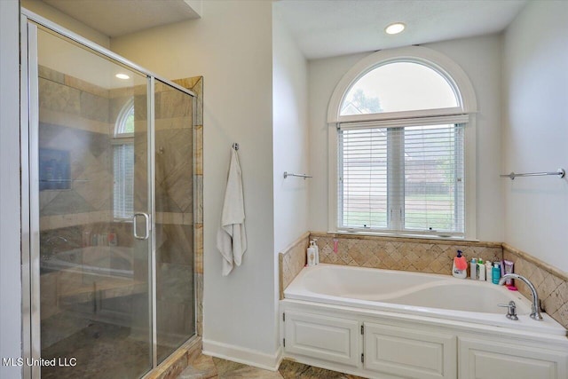 bathroom with a garden tub, healthy amount of natural light, and a shower stall