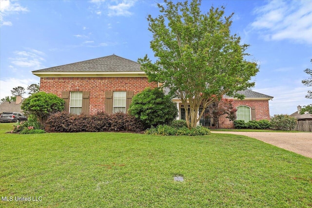 view of front of house featuring brick siding, a front lawn, and roof with shingles