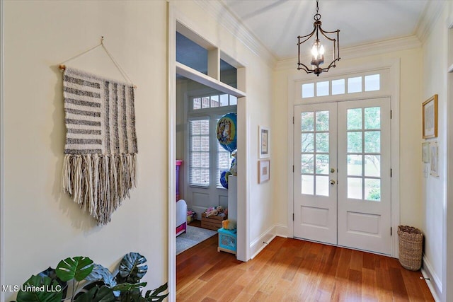 entryway featuring french doors, wood finished floors, ornamental molding, a chandelier, and baseboards