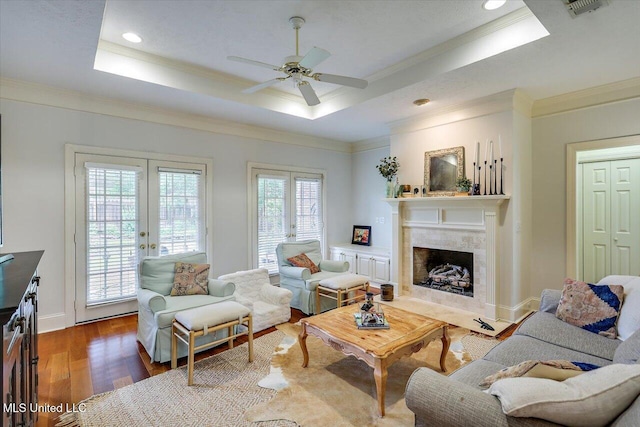 living area featuring a tray ceiling, french doors, a ceiling fan, ornamental molding, and wood finished floors