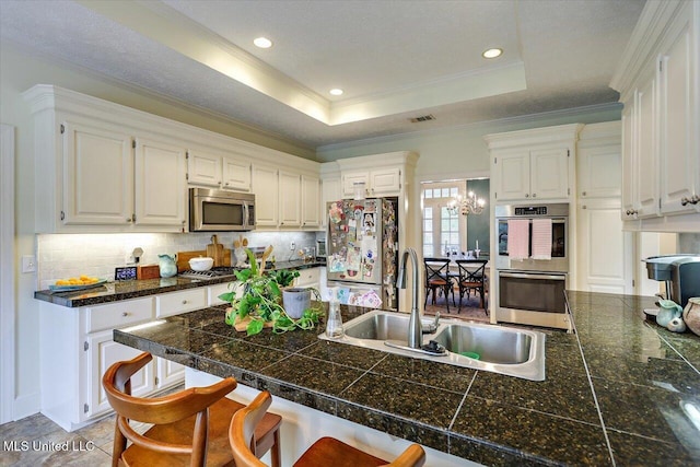 kitchen with tile counters, appliances with stainless steel finishes, a sink, a kitchen bar, and tasteful backsplash