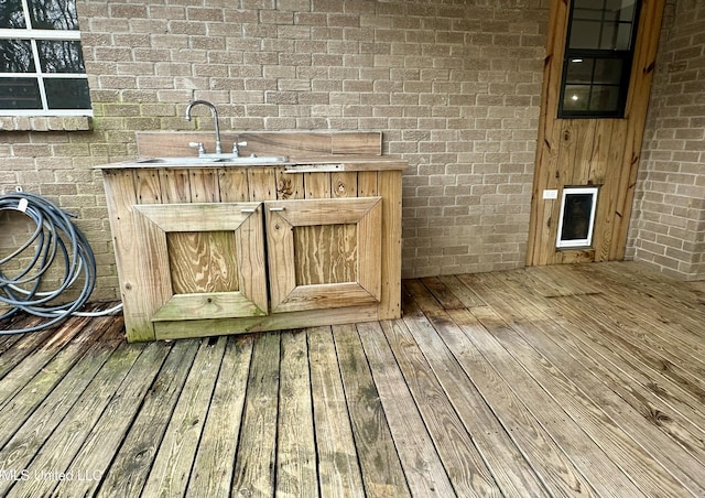 exterior space featuring wood-type flooring, a sink, and brick wall