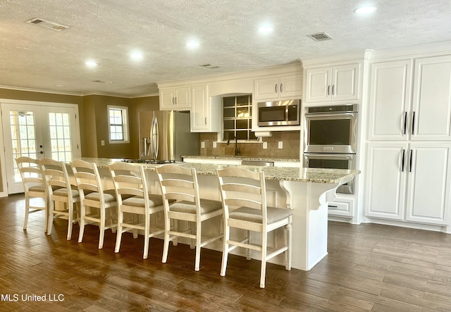 kitchen featuring a center island, appliances with stainless steel finishes, decorative backsplash, dark wood finished floors, and crown molding