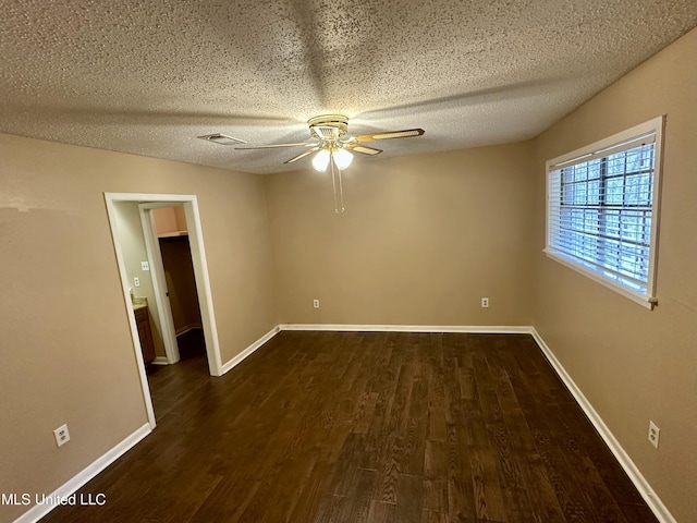 unfurnished room featuring ceiling fan, baseboards, dark wood finished floors, and a textured ceiling