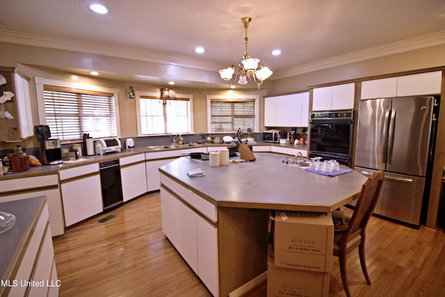 kitchen featuring a center island, a notable chandelier, decorative light fixtures, white cabinets, and appliances with stainless steel finishes