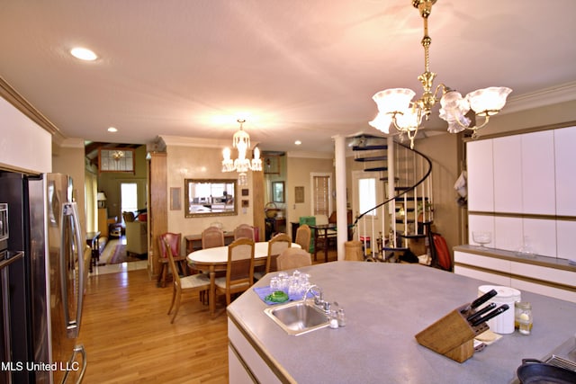 kitchen featuring stainless steel refrigerator, white cabinetry, crown molding, and pendant lighting