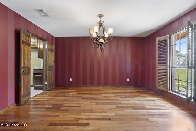 unfurnished dining area with light wood-style flooring, visible vents, an inviting chandelier, and a healthy amount of sunlight