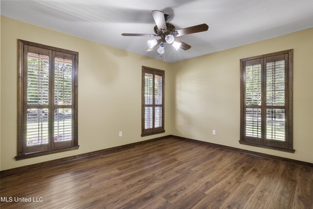 unfurnished room with baseboards, a healthy amount of sunlight, dark wood-style floors, and ceiling fan