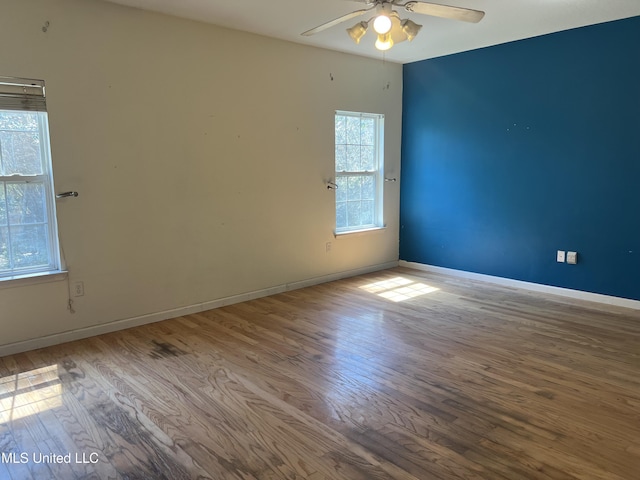 empty room with ceiling fan, baseboards, and wood finished floors