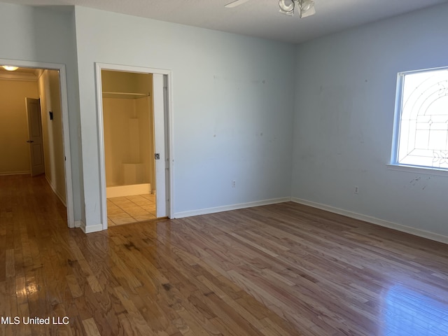 interior space with baseboards, wood finished floors, and a ceiling fan