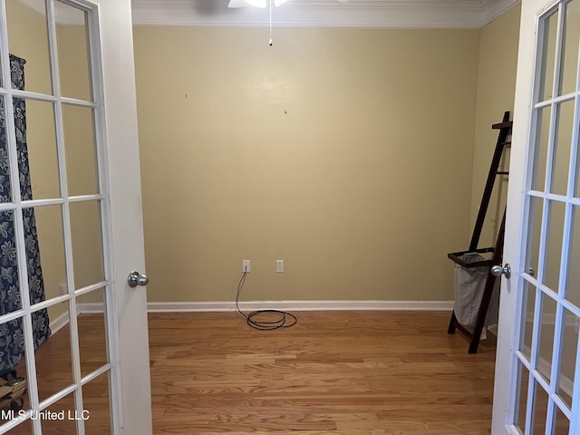 spare room featuring french doors, wood finished floors, baseboards, and ornamental molding