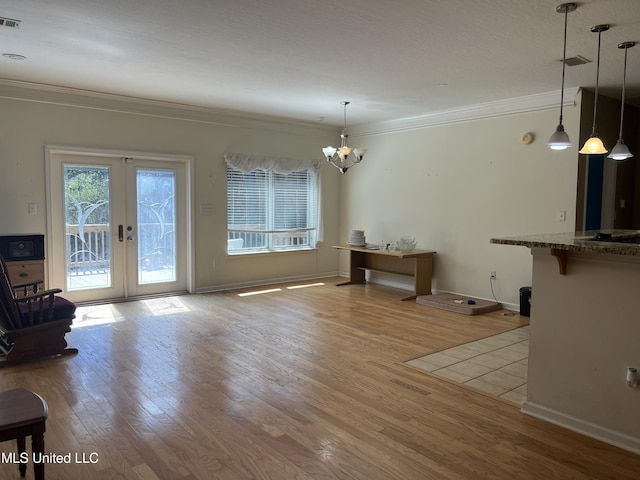 unfurnished living room with visible vents, french doors, crown molding, and wood finished floors