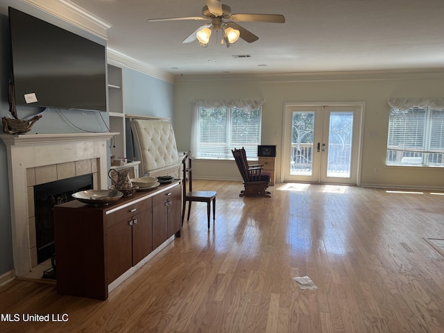 interior space featuring wood finished floors, visible vents, ornamental molding, a tile fireplace, and french doors