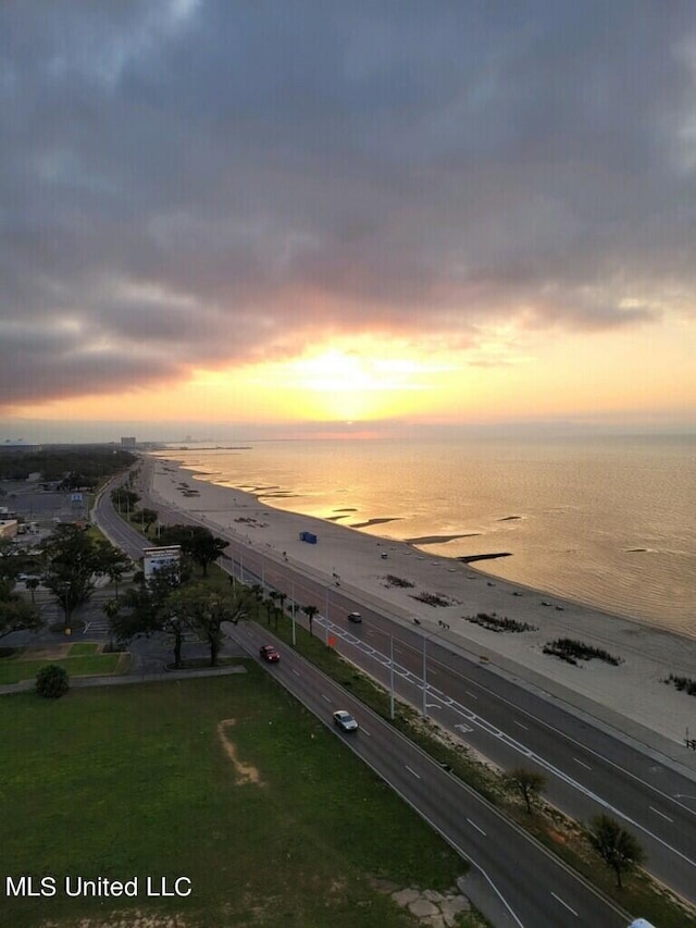 aerial view at dusk with a water view and a view of the beach