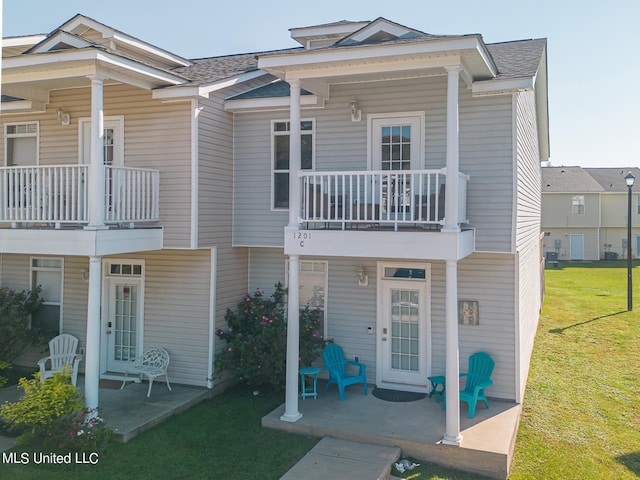 view of front of home with a patio, a balcony, and a front lawn