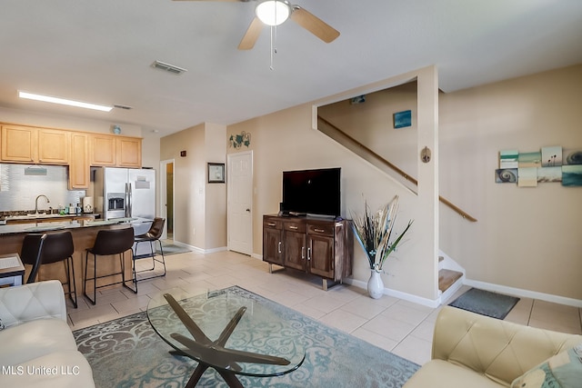 living room featuring sink, light tile patterned floors, and ceiling fan