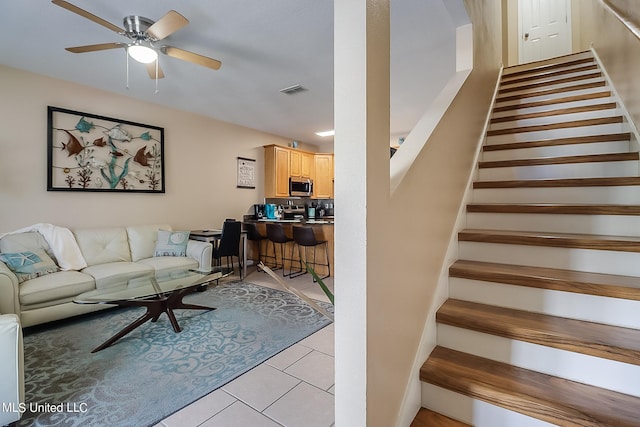 stairs featuring ceiling fan