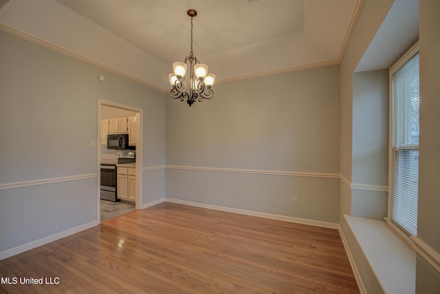 spare room with a tray ceiling, crown molding, an inviting chandelier, and light wood-type flooring