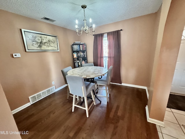 dining space featuring visible vents, a textured ceiling, and a chandelier