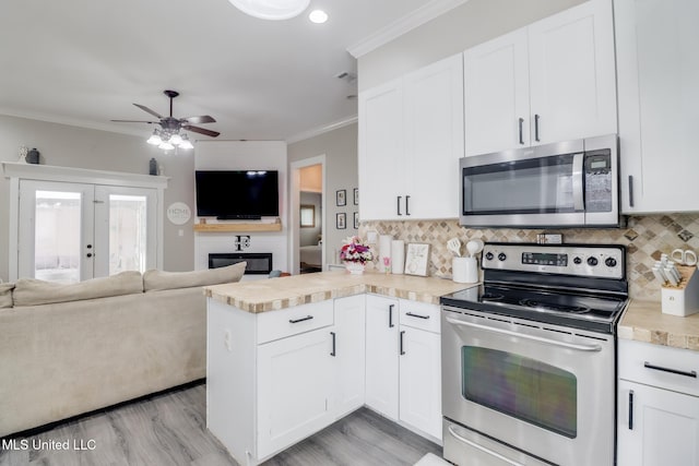 737 Ieke Cir, Diamondhead, MS 39525 - kitchen featuring appliances with stainless steel finishes, a peninsula, open floor plan, backsplash, and ornamental molding