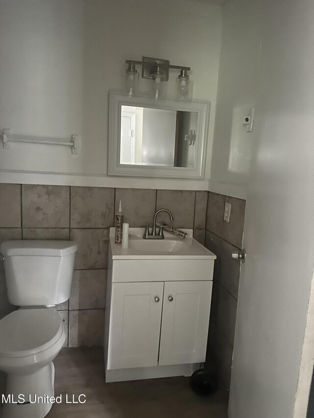 2806 Tara Rd, Jackson, MS 39212 - half bathroom with tile walls, vanity, toilet, wainscoting, and wood finished floors