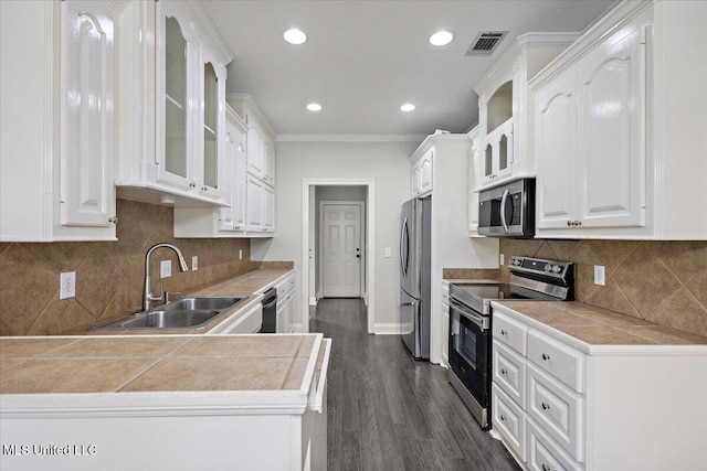 kitchen featuring stainless steel appliances, tile counters, white cabinetry, and sink