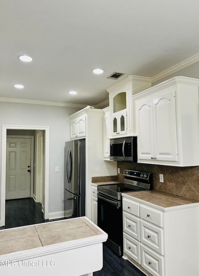 kitchen with ornamental molding, stainless steel appliances, backsplash, dark hardwood / wood-style floors, and white cabinets